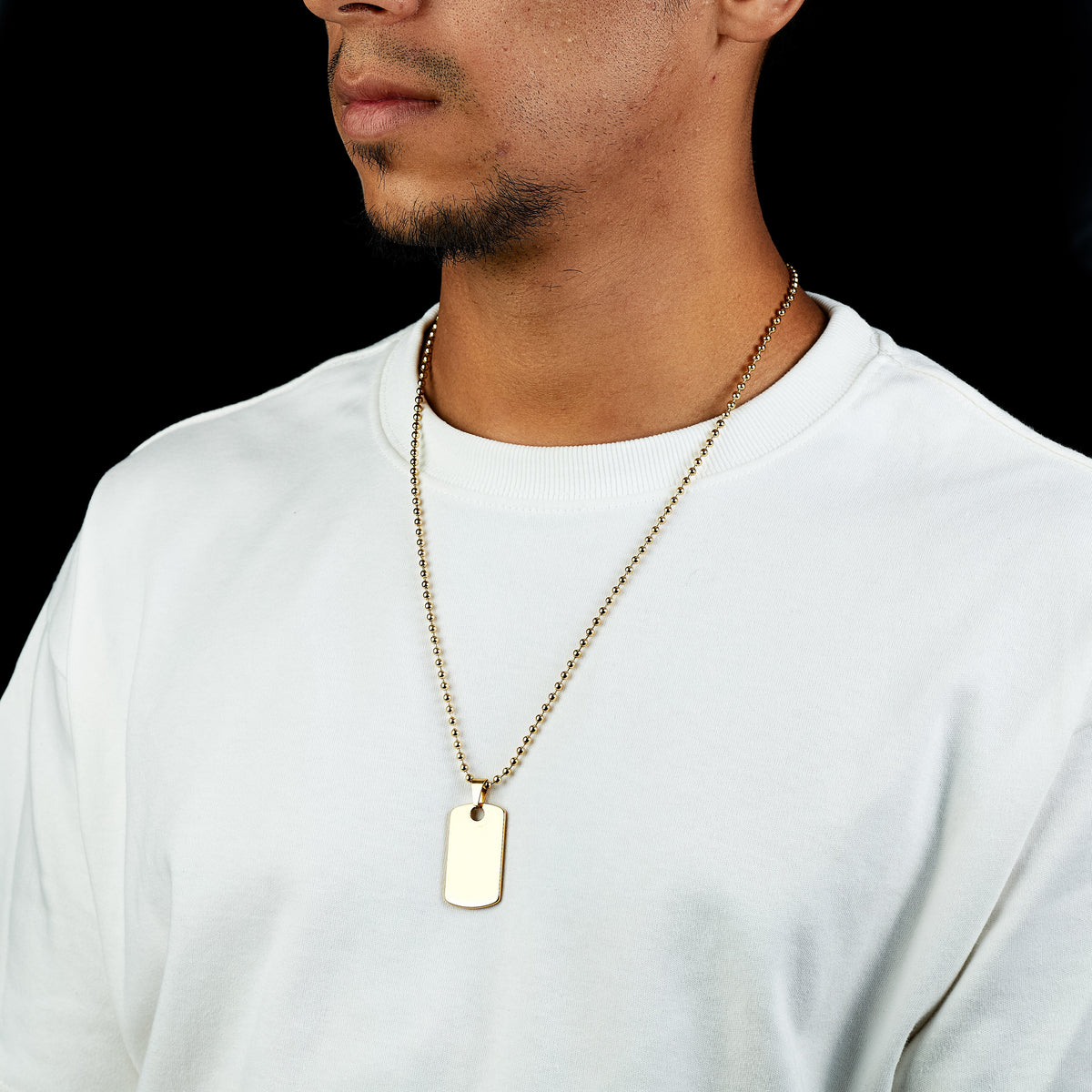 Dije Placa Identidad ORIGGEN aislado en oro laminado 18K sobre titanio, diseño limpio y sobrio, fondo neutro